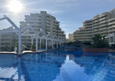 Piscina grande con puente y bar hawaino en Benal Beach Hub